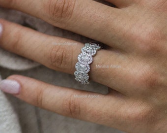 May include: A silver band ring with a row of oval-shaped diamonds. The ring is on a person's finger.