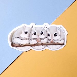 May include: Three adorable gray and white flying squirrels are sitting on a branch, each holding a small heart-shaped object. The squirrels are looking at the viewer and have big, round eyes. The image is surrounded by a white border and includes the text "Upbeatpals" in the upper right corner.
