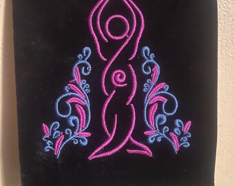 May include: A black velvet pouch with a pink and blue embroidered design of a woman with a crescent moon above her head. The design is surrounded by floral motifs.