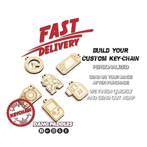 May include: A collection of six light-colored wooden keychain charms in various shapes including a camera, game console, and geometric designs. Text reads FAST DELIVERY, BUILD YOUR CUSTOM KEY-CHAIN, PERSONALIZED, SEND US YOUR IMAGE AFTER PURCHASE, WE FINISH QUICKLY AND SEND OUT ASAP, DANG PADDLES, and BUILD YOUR KEYCHAIN TODAY.