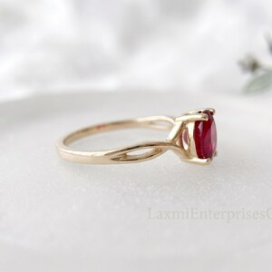 Profile view of ruby solitaire ring in 925 sterling silver with unique twisted shank and vibrant red oval gemstone.