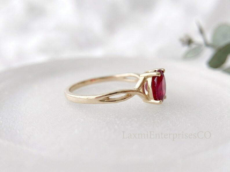 Profile view of ruby solitaire ring in 925 sterling silver with unique twisted shank and vibrant red oval gemstone.