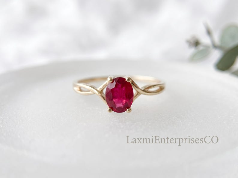 Oval ruby gemstone ring in 925 sterling silver with elegant twisted band design, minimalist engagement ring photographed on a white background.