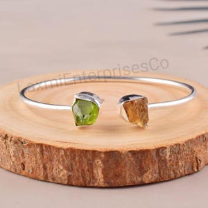 Op de afbeelding: Een zilveren armband met twee ruwe edelsteen accenten. De armband heeft een groene peridoot en een gele citrien.