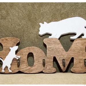 May include: Wooden "Home" sign with hooks, featuring a white silhouette of a cat on top and a white silhouette of a mouse on the "H".