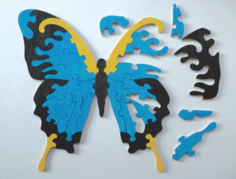Pu&ograve; includere: Un puzzle di legno a forma di farfalla blu e nero con accenti gialli. Il puzzle &egrave; composto da molti piccoli pezzi e mancano alcuni pezzi.