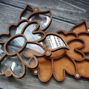 May include: A wooden flower-shaped box with a clear glass insert. The box is made of light brown wood and has a natural finish. The glass insert is clear and allows you to see the contents of the box.