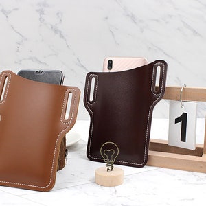 以下が含まれることがあります： 茶色と濃い茶色の革製携帯電話ケース2つ。白いステッチとベルトループが付いています。ケースはスマートフォンを収納するように設計されています。背景は大理石の表面です。