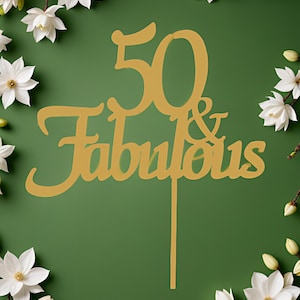 May include: Gold-colored cake topper with the number 50 and the words "& Fabulous" on a green background with white flowers.
