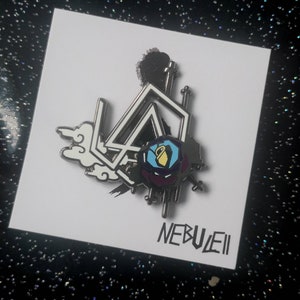 K&ouml;nnte beinhalten: Ein silberfarbener Emaille-Pin mit einem geometrischen Design, einer Rose und Wolkenmotiven. Der Pin tr&auml;gt das Wort "NEBUEII" in einer stilisierten Schriftart. Das Design beinhaltet die Farben Schwarz, Wei&szlig;, Blau, Gelb und Lila.