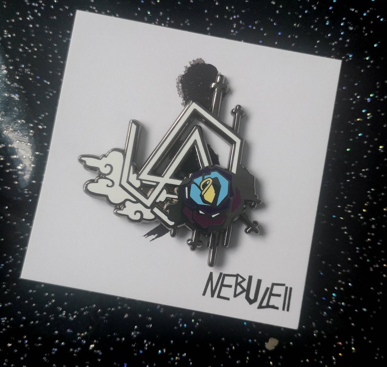 K&ouml;nnte beinhalten: Ein silberfarbener Emaille-Pin mit einem geometrischen Design, einer Rose und Wolkenmotiven. Der Pin tr&auml;gt das Wort "NEBUEII" in einer stilisierten Schriftart. Das Design beinhaltet die Farben Schwarz, Wei&szlig;, Blau, Gelb und Lila.