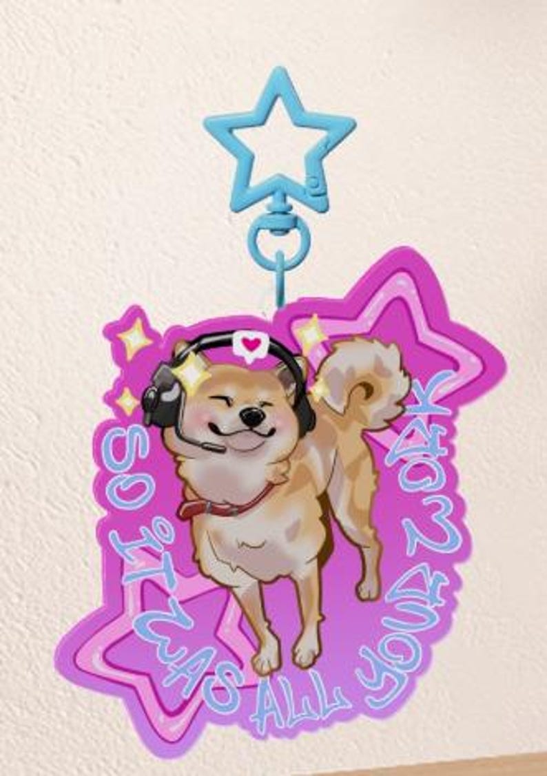 May include: A light brown Shiba Inu dog wearing a headset and a red collar, smiling. The dog is on a pink star-shaped background with the text "SO IT WAS ALL YOUR FAULT" in blue. A blue star-shaped clip is attached.