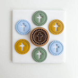 Puede incluir: Un conjunto de seis cortadores de galletas redondos con un diseño de cruz. Los cortadores son de varios colores, incluyendo verde, azul, amarillo y marrón. Los cortadores están dispuestos en un círculo sobre una superficie blanca.