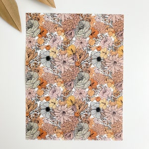 May include: A floral pattern featuring a variety of flowers in shades of peach, orange, pink, and gray, with black outlines. The design is on a white background, with dried leaves in the upper left corner.