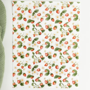 May include: A white background with a repeating pattern of red strawberries, green leaves, and white flowers.