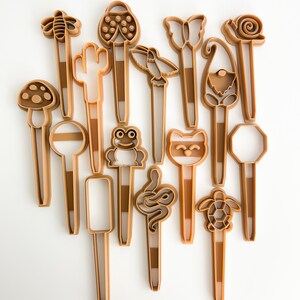 May include: A set of 16 brown plastic cookie cutters shaped like various animals, insects, and plants. The cutters are all about 4 inches long and have a handle on the top.