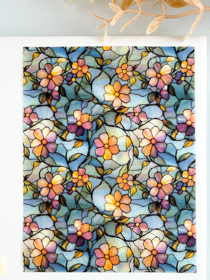Pu&ograve; includere: Pannello decorativo con un design floreale a vetrata. Il motivo include fiori nei toni dell'arancione, del rosa e del viola, su uno sfondo azzurro. Linee scure definiscono le forme floreali e le foglie.