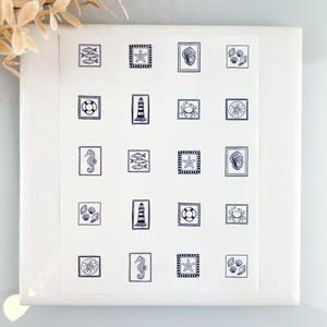 Pode incluir: Um quadrado branco com uma coleção de ilustrações de temática náutica em azul marinho. Os desenhos incluem peixes, estrelas do mar, conchas, um salva-vidas, um farol, um caranguejo, uma bússola e um cavalo-marinho. As ilustrações estão dispostas em uma grade.