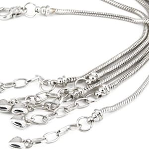 May include: A silver chain necklace with multiple strands and a lobster clasp. The necklace has several heart-shaped charms attached to it.