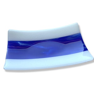 May include: A white glass serving dish with blue and white stripes. The dish is slightly curved and has a glossy finish.