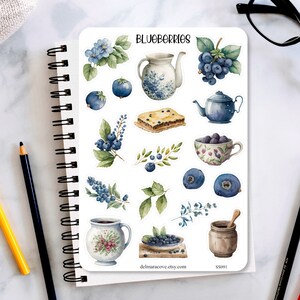 May include: A sticker sheet featuring watercolor illustrations of blueberries, teapots, teacups, and pastries. The word "BLUEBERRIES" is at the top. The stickers are in shades of blue, green, and brown, with a white background.