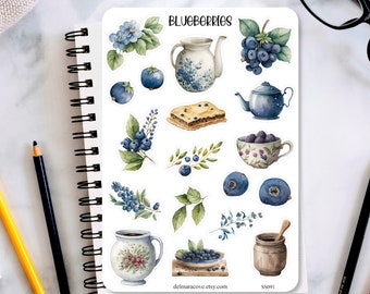 May include: A sticker sheet featuring watercolor illustrations of blueberries, teapots, teacups, and pastries. The word "BLUEBERRIES" is at the top. The stickers are in shades of blue, green, and brown, with a white background.