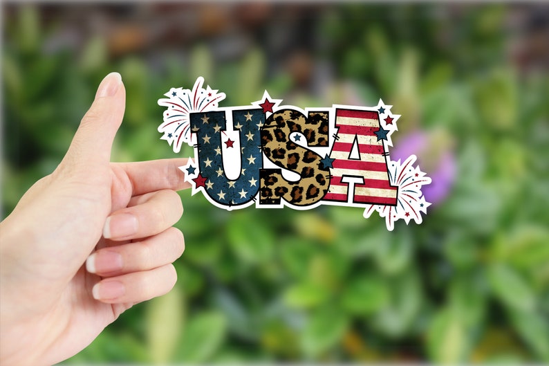 May include: A sticker with the word "USA" in large, bold letters. The letters are decorated with a red, white, and blue American flag pattern, a leopard print pattern, and fireworks.