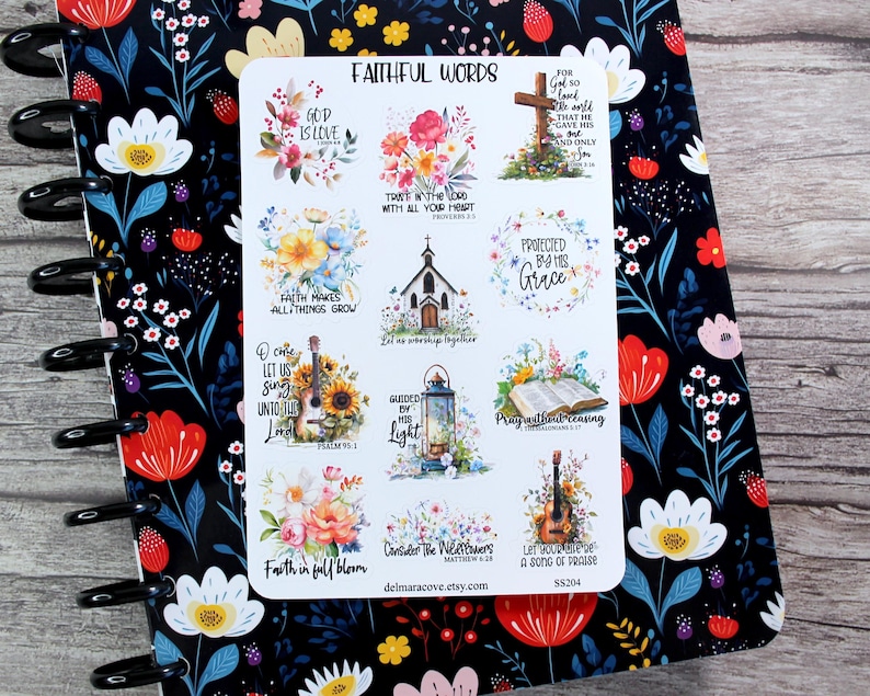 May include: A sheet of stickers with the words "FAITHFUL WORDS" at the top. The stickers feature floral designs, a cross, a church, a guitar, and inspirational quotes. The stickers are on a floral patterned notebook.
