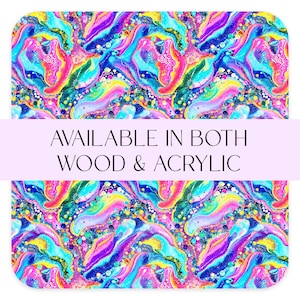 May include: Two rectangular items with rounded corners feature a vibrant, abstract design in shades of blue, purple, pink, yellow, and green. The text "AVAILABLE IN BOTH WOOD & ACRYLIC" is displayed in a white font.