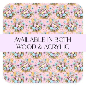 May include: A pink background with a repeating pattern of pastel blue, yellow, and pink eggs in a nest with flowers and gold glitter. The text "AVAILABLE IN BOTH WOOD & ACRYLIC" is displayed in a purple banner.