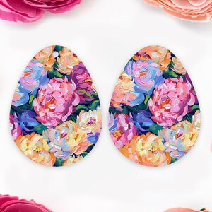 May include: Two egg-shaped earrings with a floral design. The earrings feature a vibrant mix of pink, purple, yellow, and blue flowers against a dark background. Each earring has a small hole at the top for hanging.
