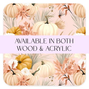 May include: A seamless pattern featuring white and orange pumpkins, autumn foliage, and dried grasses on a light pink background. The text "AVAILABLE IN BOTH WOOD & ACRYLIC" is displayed across the middle of the image.