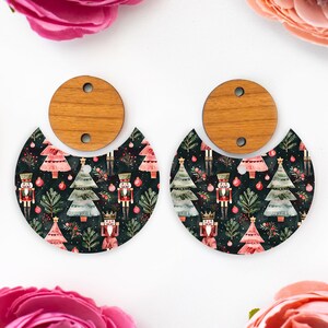 May include: A pair of Christmas-themed earrings. The earrings feature a wooden top with a half-circle design below, adorned with a festive pattern of Christmas trees, nutcrackers, and ornaments on a dark background. The earrings are designed for pierced ears.