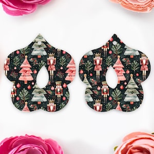 May include: Two Christmas tree-shaped ornaments with a dark background. The pattern includes nutcrackers, Christmas trees, and festive foliage. Each ornament has a central cutout and a hole for hanging, perfect for festive decor.