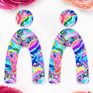 May include: A pair of colourful, abstract earrings. Each earring has a circular stud and a large, arch-shaped drop. The earrings display a swirling pattern of blues, pinks, yellows, and purples, creating a unique, artistic accessory.