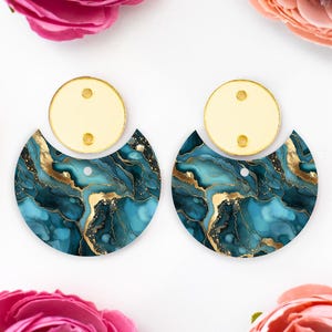 May include: A pair of blue and gold marble earrings with a gold metal backing. The earrings are in the shape of a half circle.