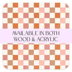 May include: A checkered pattern with alternating orange and pink squares on a white background. The text "AVAILABLE IN BOTH WOOD & ACRYLIC" is displayed on a light purple banner.