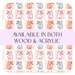 May include: A repeating pattern of cartoon bunnies in shades of pink, blue, and peach, set on a checkered background. The text "AVAILABLE IN BOTH WOOD & ACRYLIC" is displayed across the center of the image.