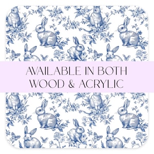 Peut inclure: Un fond blanc avec un motif floral bleu et blanc représentant des lapins. Le texte "AVAILABLE IN BOTH WOOD & ACRYLIC" est affiché sur une bannière violette.