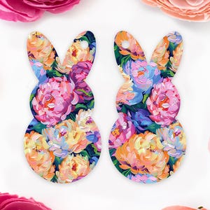 May include: Two colorful bunny shaped ornaments with a floral pattern. The bunnies are painted with pink, purple, blue, yellow, and green flowers.