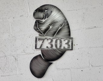 May include: Metal house number sign featuring a manatee design with the number 7303.