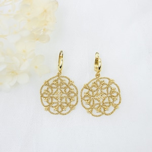 Peut inclure: Une paire de boucles d'oreilles ajourées de couleur or. Chaque boucle d'oreille présente un motif circulaire avec des motifs floraux complexes. Les boucles d'oreilles sont suspendues à un petit anneau. Le fond est blanc.