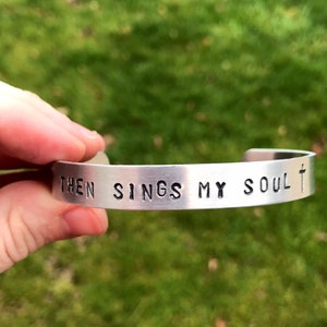 May include: Silver bracelet with the words "Then sings my soul" and a cross engraved on it.