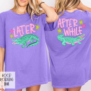 以下が含まれることがあります： 紫色のTシャツ。前面には緑色のワニのグラフィックとピンク色の「LATER」の文字が描かれています。背面には「AFTER WHILE」の文字と、お揃いのワニのグラフィックが描かれています。デザインにはピンクと黄色の星が含まれています。