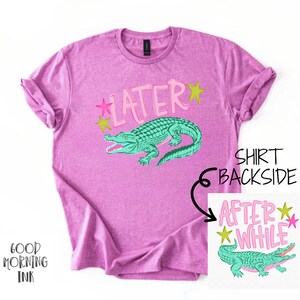 以下が含まれることがあります： ピンク色のTシャツ。 ターコイズ色のワニのグラフィックとピンク色の「LATER」の文字が特徴です。 背面には「AFTER WHILE」と書かれた小さなグラフィックもあります。 カジュアルウェアです。