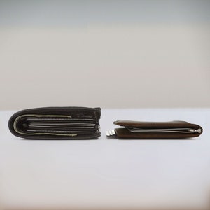 Two dark brown slim leather bifold wallets lay on top of a desk side by side. The view is from the side to show a comparison in size between the two leather bifold wallets for men. The wallet on the left is about double the height of the slim wallet on the right.