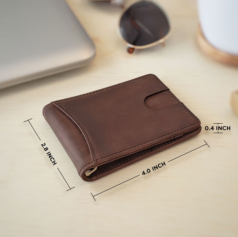 A dark brown leather slim bifold wallet lays flat on top of a desk, with measurements displaying the length, width, and height. The wallet measures 2.8 inches tall by 4 inches wide by 0.4 inches deep.