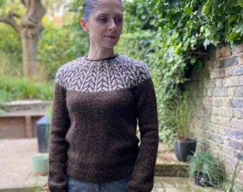May include: A brown sweater with a white and brown leaf pattern on the yoke. The sweater is made of a soft, fuzzy yarn.