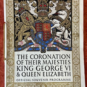 Peut inclure: Un programme blanc et or pour le couronnement du roi George VI et de la reine Élisabeth. Le programme présente un blason avec un lion et une licorne, ainsi que le texte "The Coronation of Their Majesties King George VI & Queen Elizabeth Official Souvenir Programme 2/6".