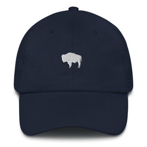 Può includere: Un berretto da baseball blu navy con una silhouette di bufalo ricamata in bianco.